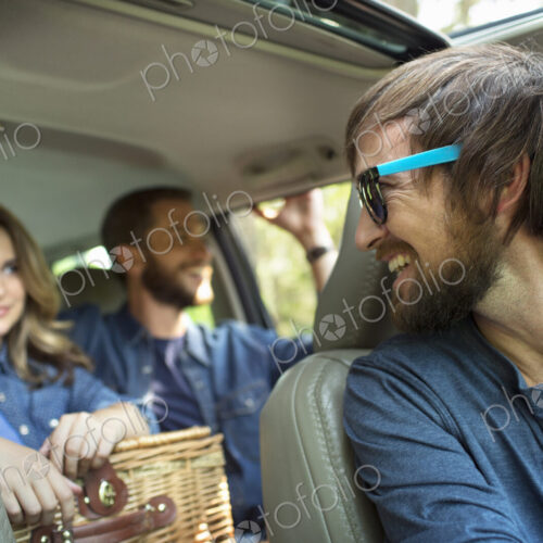 A group of people inside a car, on a road trip.