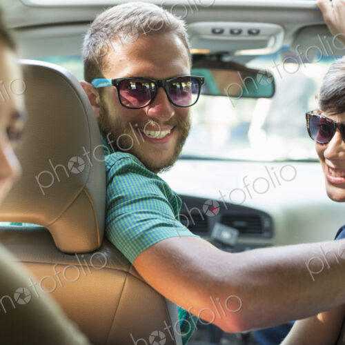 A group of people inside a car, on a road trip. View from the back seat. A group of people inside a car, on a road trip. View from the back seat.