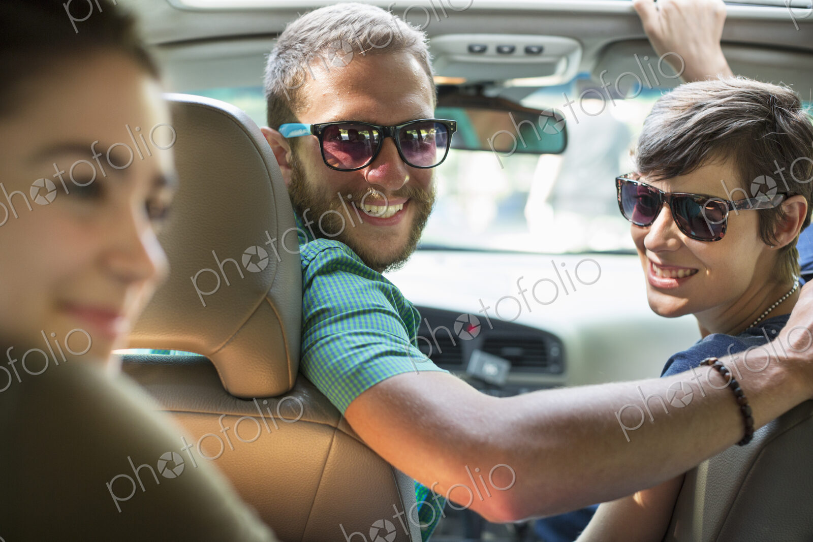 A group of people inside a car, on a road trip. View from the back seat.