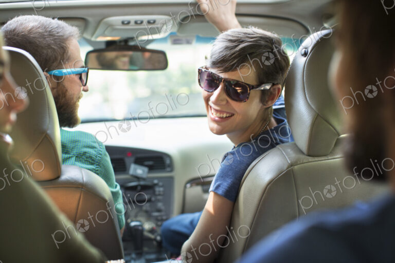 A group of people inside a car, on a road trip. View from the back seat.