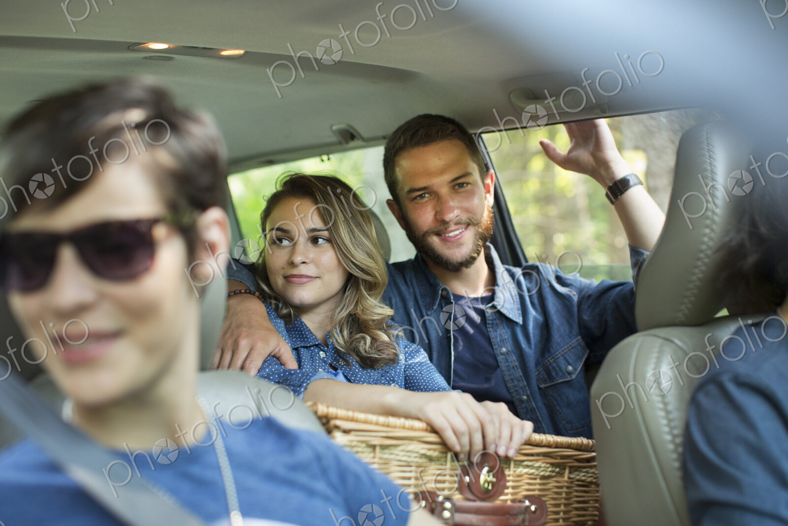 A group of people inside a car, two in the back seat and two in the front.