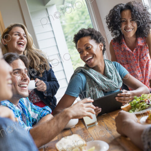 A group of people meeting in a cafe for a meal. Using digital tablets and smart phones. A group of people meeting in a cafe for a meal. Using digital tablets and smart phones.