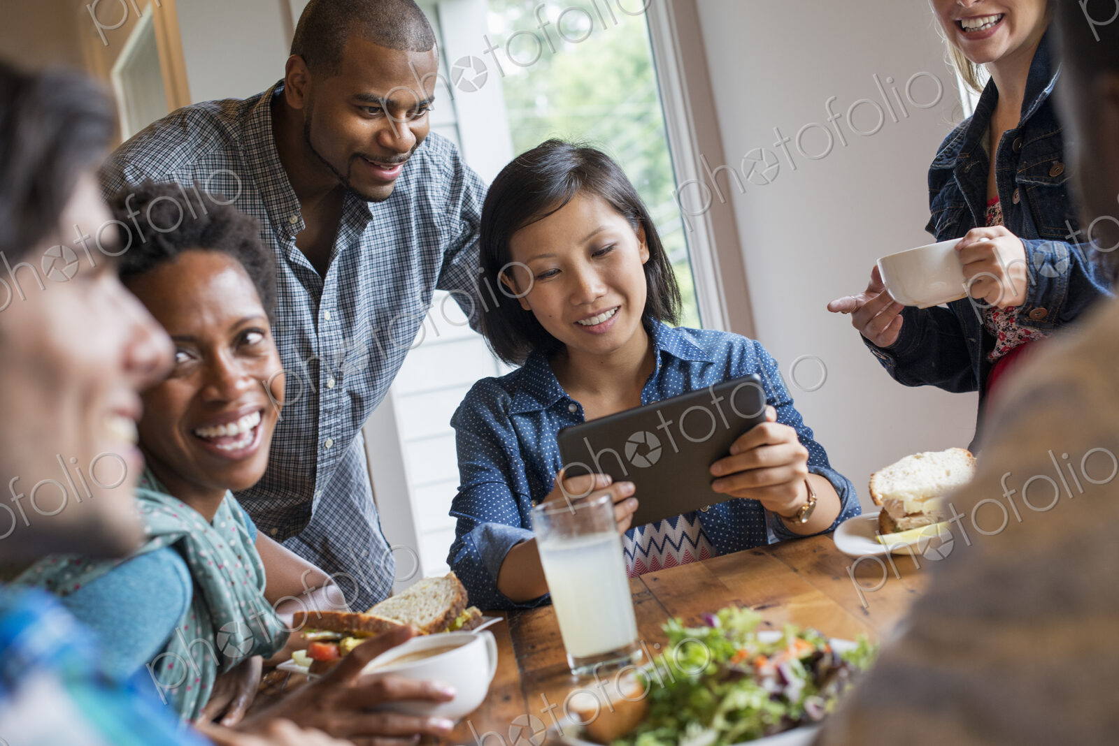 A group of people meeting in a cafe for a meal. Using digital tablets and smart phones.