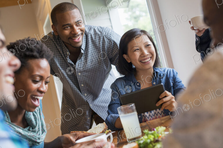 A group of people meeting in a cafe for a meal. Using digital tablets and smart phones.