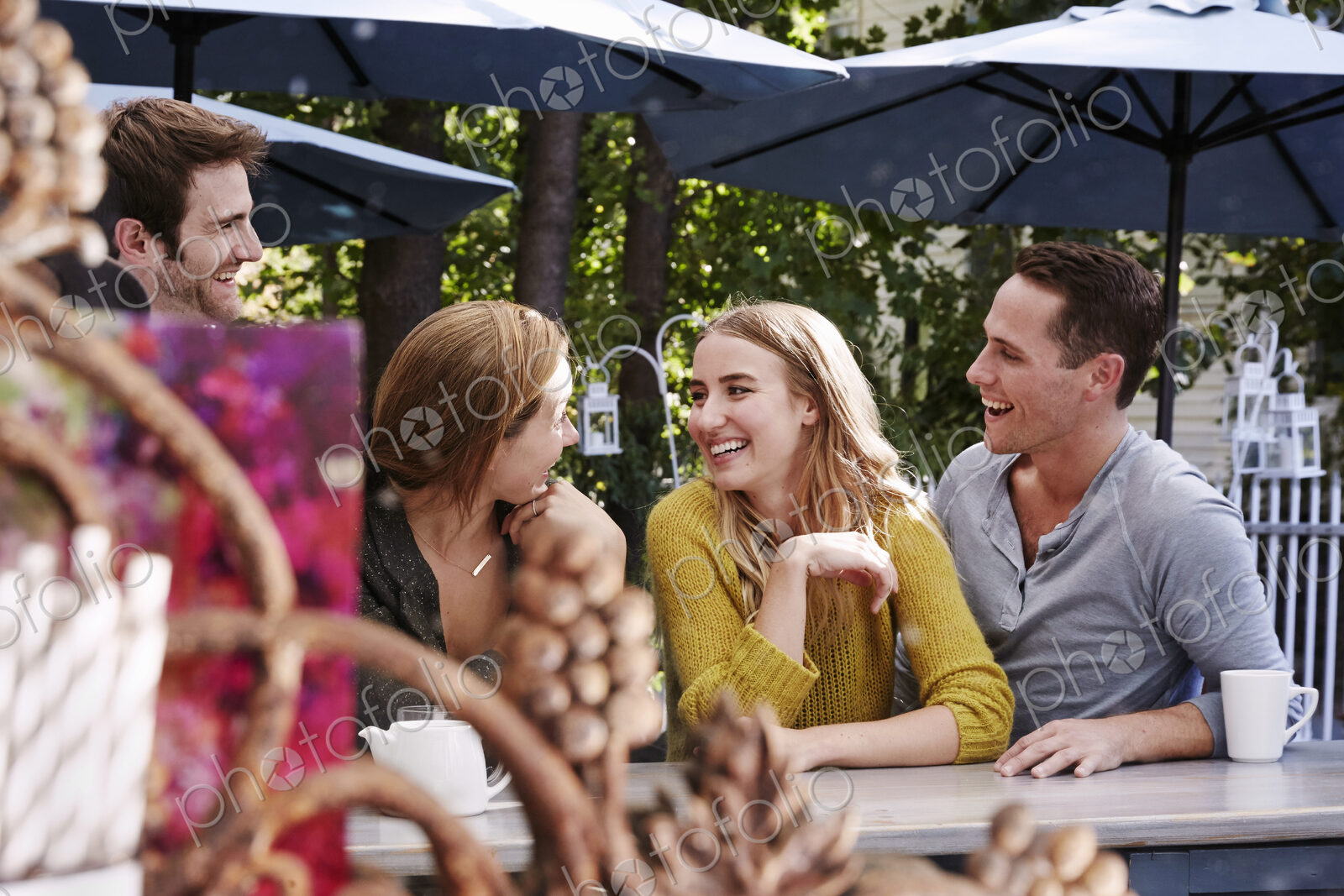 A group of people sitting at a long table in an outdoor cafe.