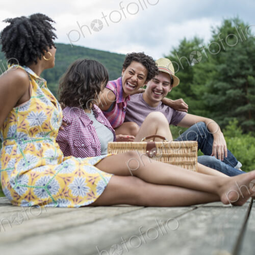 A group of people sitting on a woode pier overlooking a lake. A group of people sitting on a woode pier overlooking a lake.