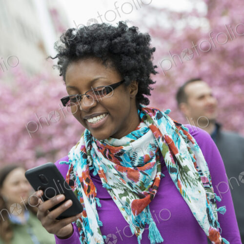 A group of people under the cherry blossom trees in the park. A young woman smiling…
