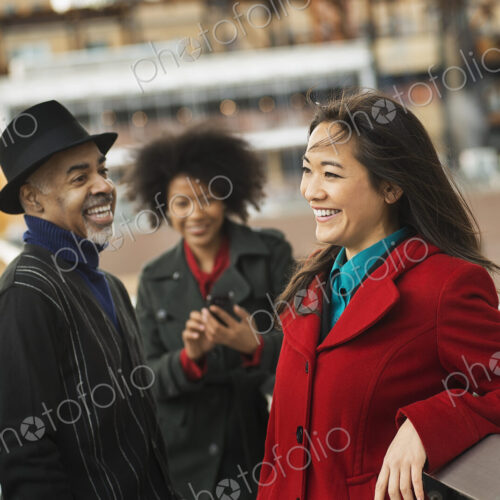 A group of people using mobile phones, and talking to each other. A group of people using mobile phones, and talking to each other.