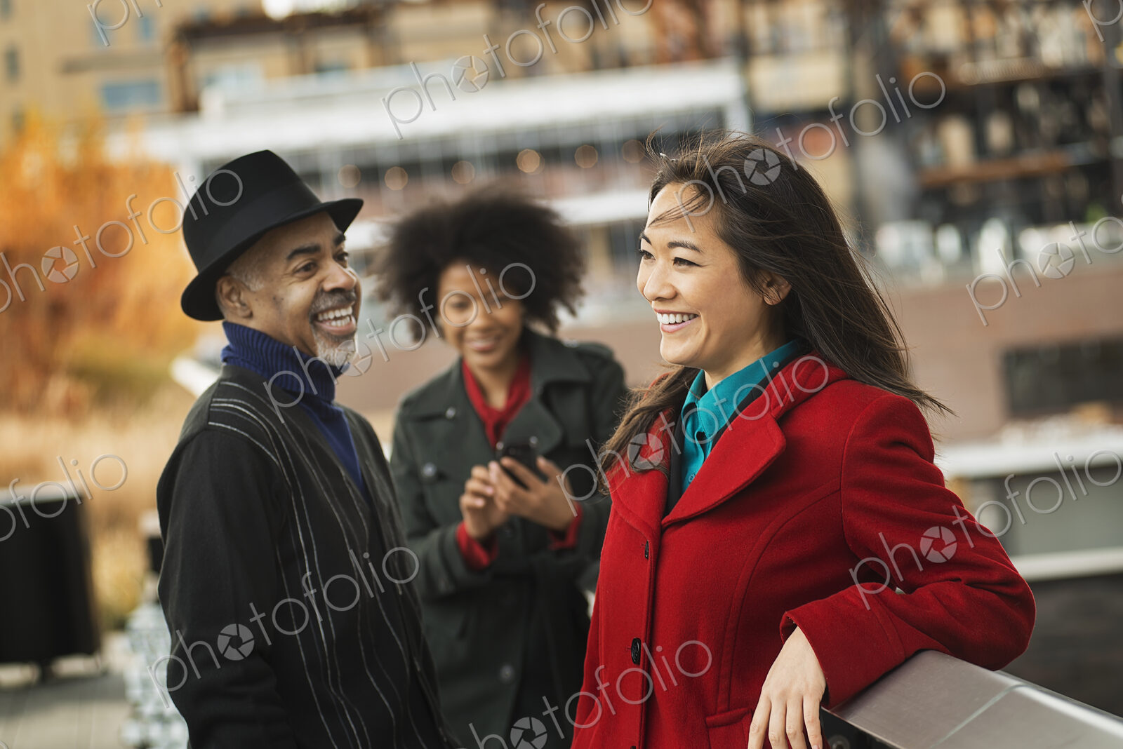 A group of people using mobile phones, and talking to each other.