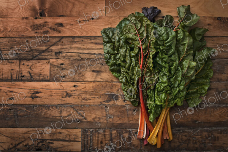 A group of red and orange chard leaves with bright coloured stems. Organic vegetables,…