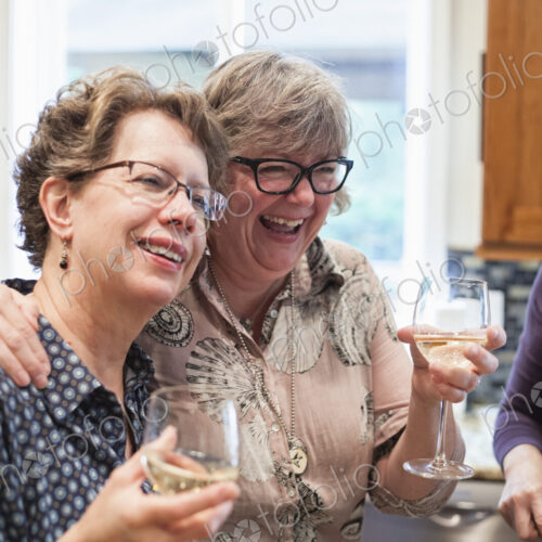 A group of senior women friends having some wine at a home dinner party.