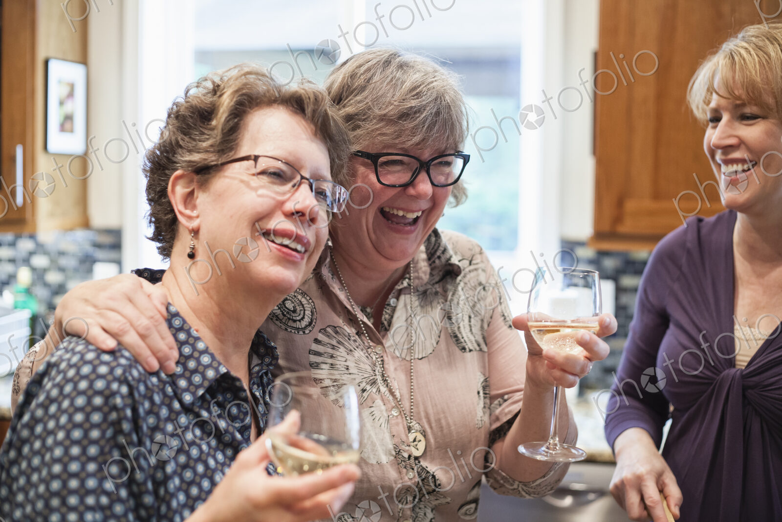 A group of senior women friends having some wine at a home dinner party.