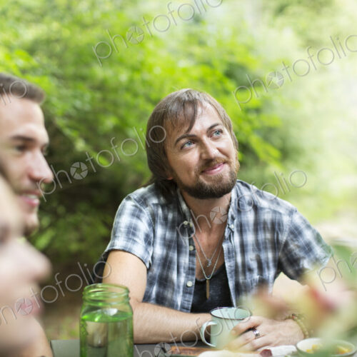 A group of three friends seated outdoors having a meal.