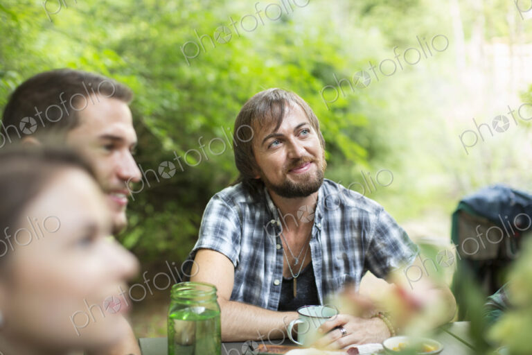 A group of three friends seated outdoors having a meal.