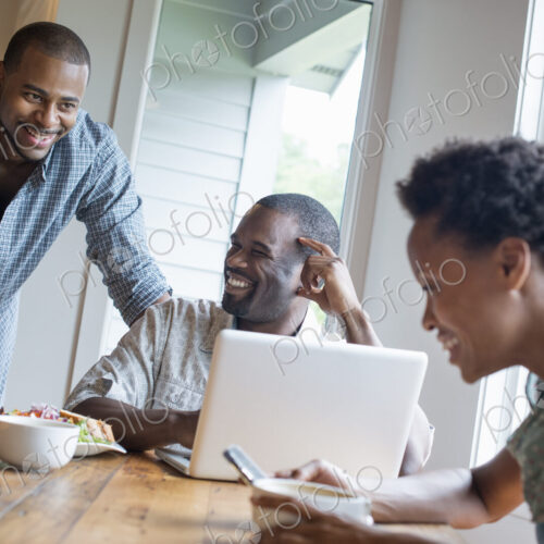 A group of three people in a cafe. Sharing a laptop and using smart phones. A group of three people in a cafe. Sharing a laptop and using smart phones.