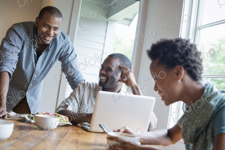 A group of three people in a cafe. Sharing a laptop and using smart phones.