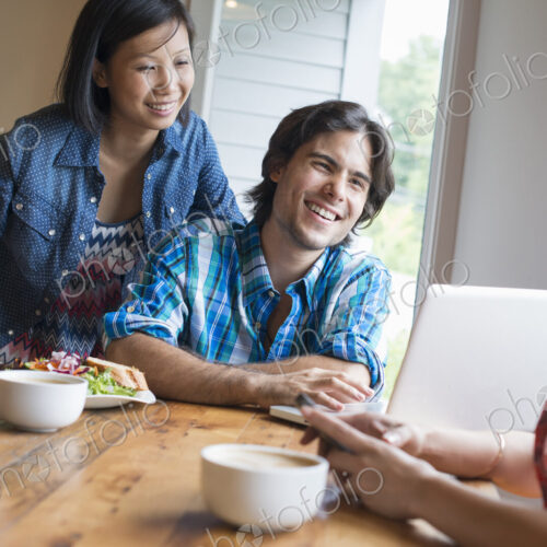 A group of three people in a cafe. Sharing a laptop and using smart phones. A group of three people in a cafe. Sharing a laptop and using smart phones.