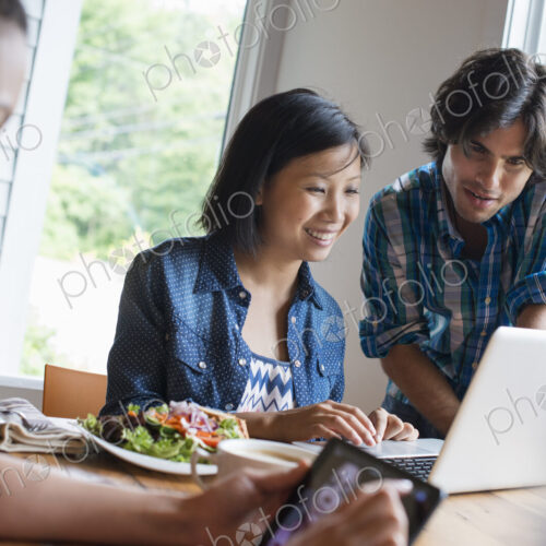 A group of three people in a cafe. Sharing a laptop and using smart phones. A group of three people in a cafe. Sharing a laptop and using smart phones.