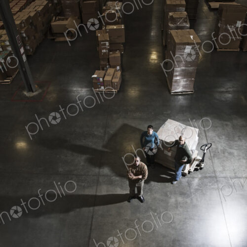 A group of three warehouse workers standing in the center of a distirbution warehouse.
