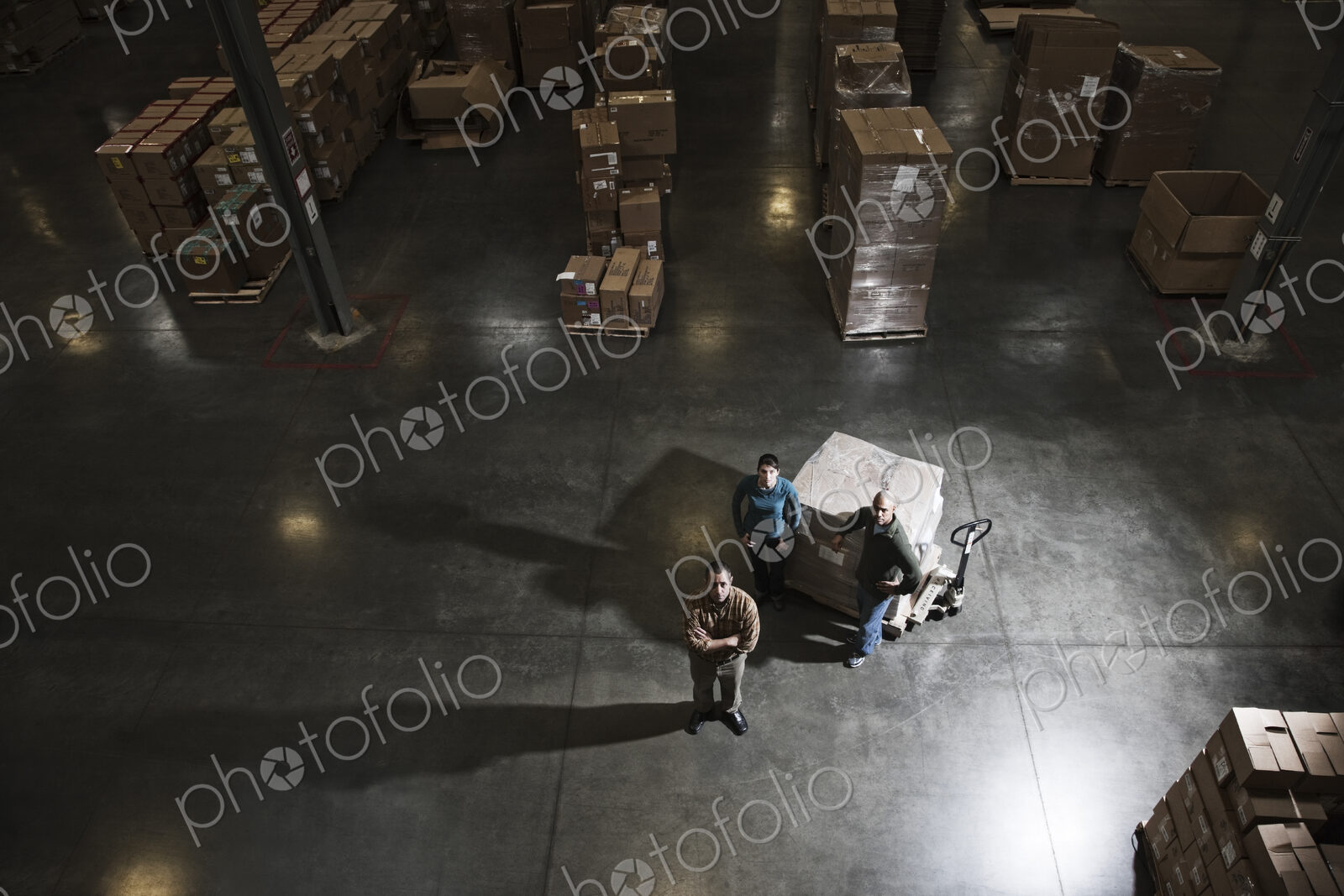 A group of three warehouse workers standing in the center of a distirbution warehouse.