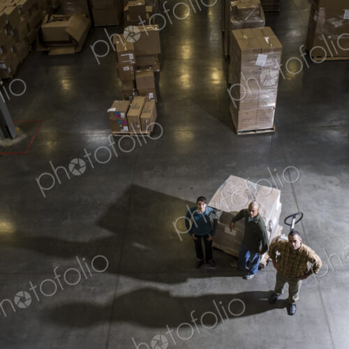 A group of three warehouse workers standing in the center of a distirbution warehouse. A group of three warehouse workers standing in the center of a distirbution warehouse.