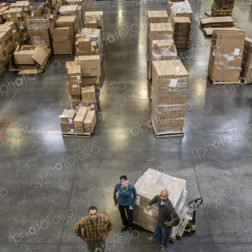 A group of three warehouse workers standing in the center of a distirbution warehouse. A group of three warehouse workers standing in the center of a distirbution warehouse.
