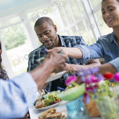 A group of women and men around a table sharing a meal in a farmhouse kitchen.