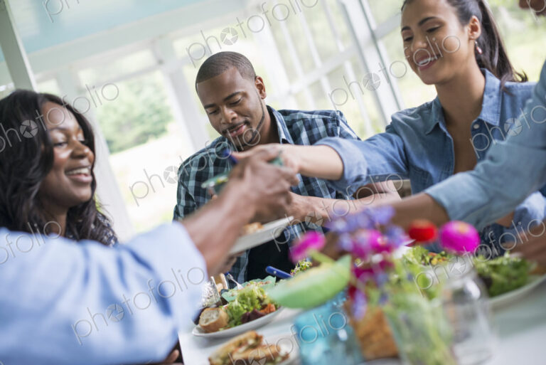 A group of women and men around a table sharing a meal in a farmhouse kitchen.