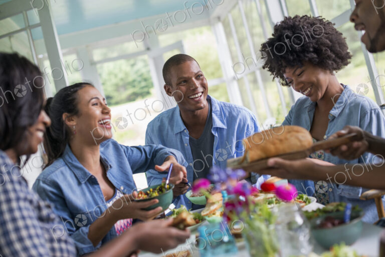 A group of women and men around a table sharing a meal in a farmhouse kitchen.