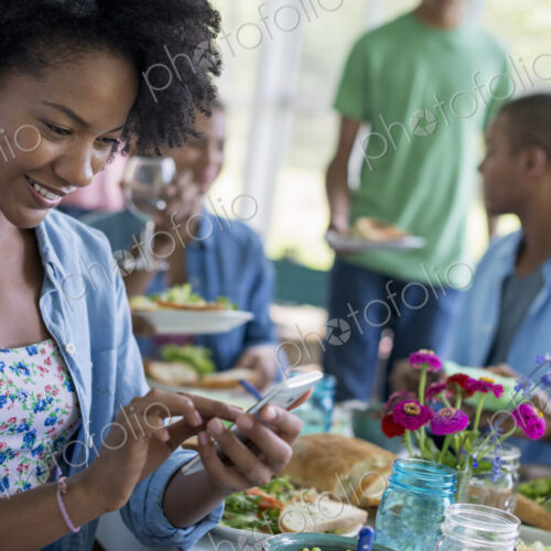 A group of women and men around a table sharing a meal in a farmhouse kitchen. A group of women and men around a table sharing a meal in a farmhouse kitchen.