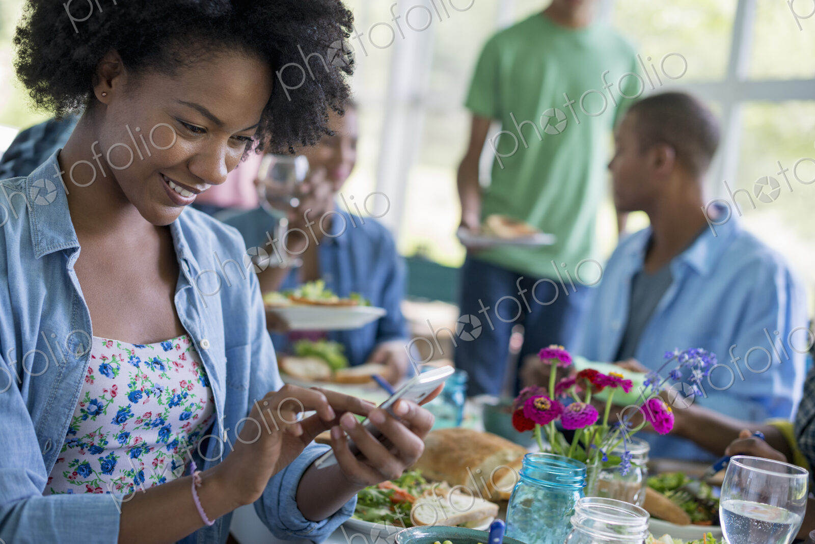 A group of women and men around a table sharing a meal in a farmhouse kitchen.