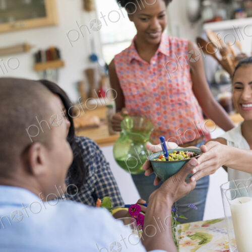 A group of women and men at a meal in a farmhouse kitchen.