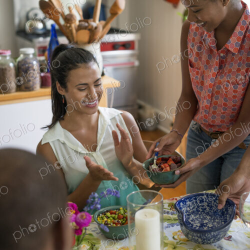 A group of women and men at a meal in a farmhouse kitchen.