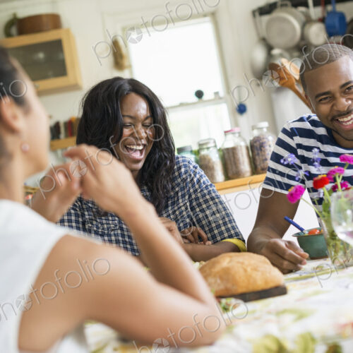A group of women and men at a meal in a farmhouse kitchen.