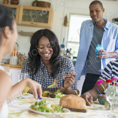 A group of women and men at a meal in a farmhouse kitchen.