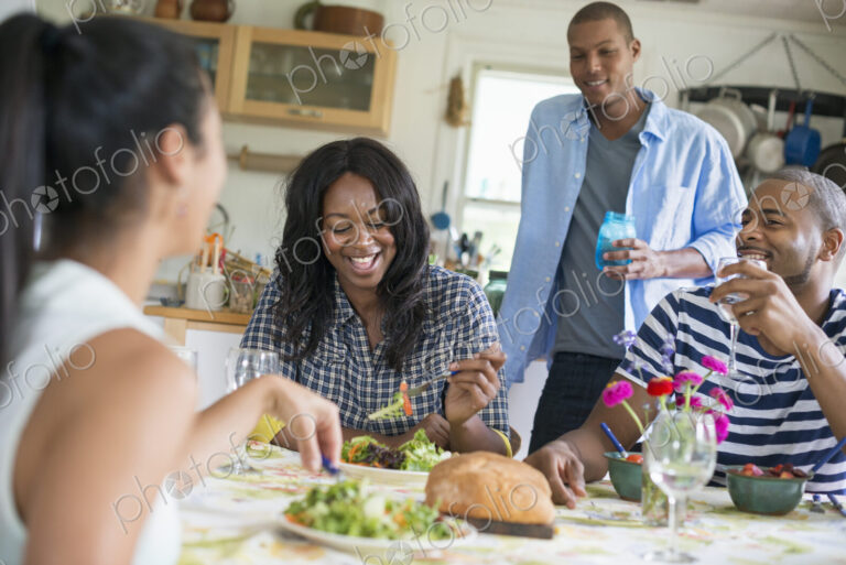 A group of women and men at a meal in a farmhouse kitchen.