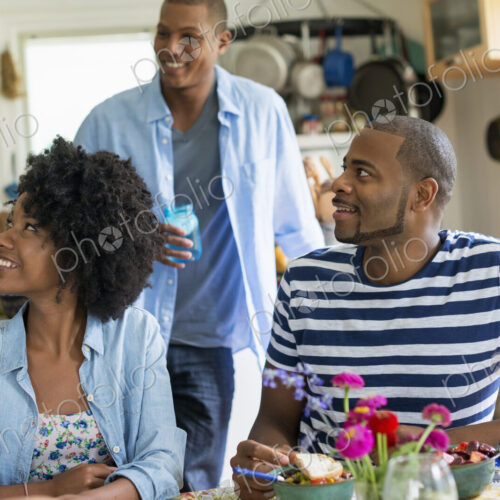 A group of women and men at a meal in a farmhouse kitchen.