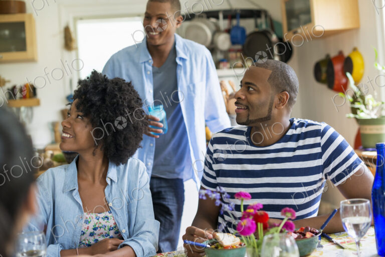 A group of women and men at a meal in a farmhouse kitchen.