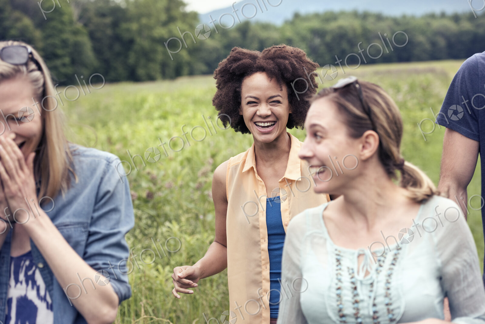 A group of women walking through a meadow in the countryside laughing.