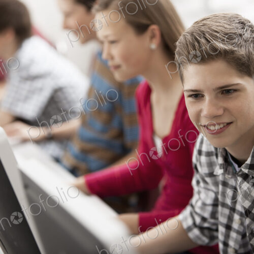 A group of young people, boys and girls, working at computer screens in class. A group of young people, boys and girls, working at computer screens in class.