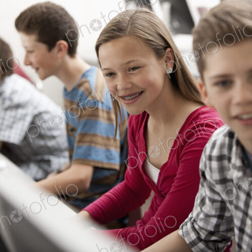 A group of young people, boys and girls, working at computer screens in class. A group of young people, boys and girls, working at computer screens in class.