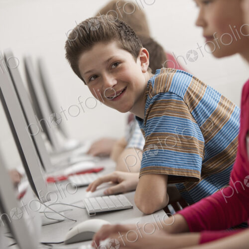 A group of young people, boys and girls, working at computer screens in class. A group of young people, boys and girls, working at computer screens in class.