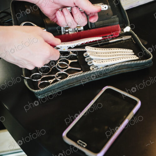 A hair salon desk, a smart phone, and a woman's hand reaching into a pouch for… A hair salon desk, a smart phone, and a woman's hand reaching into a pouch for…
