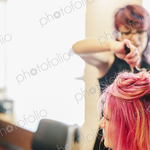 A hair stylist blowdrying a client's long pink dyed hair. A hair stylist blowdrying a client's long pink dyed hair.