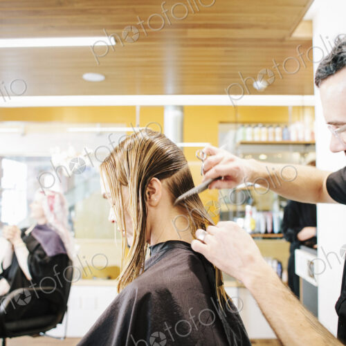 A hair stylist with a client, combing her long hair in sections. A hair stylist with a client, combing her long hair in sections.