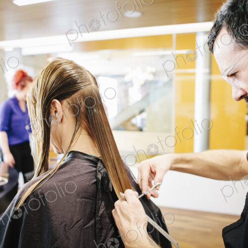 A hair stylist with a client, cutting her long straight hair. A hair stylist with a client, cutting her long straight hair.