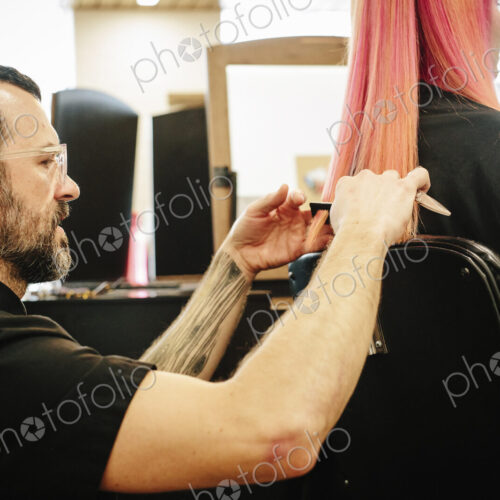 A hair stylist with a client, cutting her long straight hair, trimming the ends. A hair stylist with a client, cutting her long straight hair, trimming the ends.