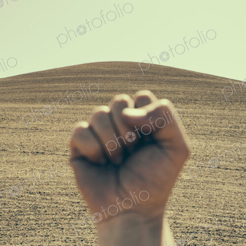 A hand bunched up and making a fist, in a gesture of defiance or determination,…