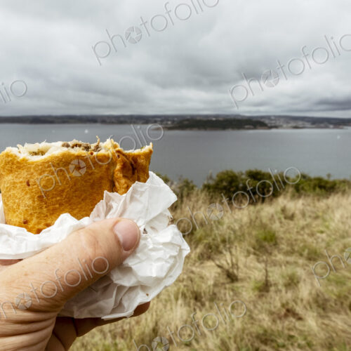 A hand holding a half eaten Cornish pasty.