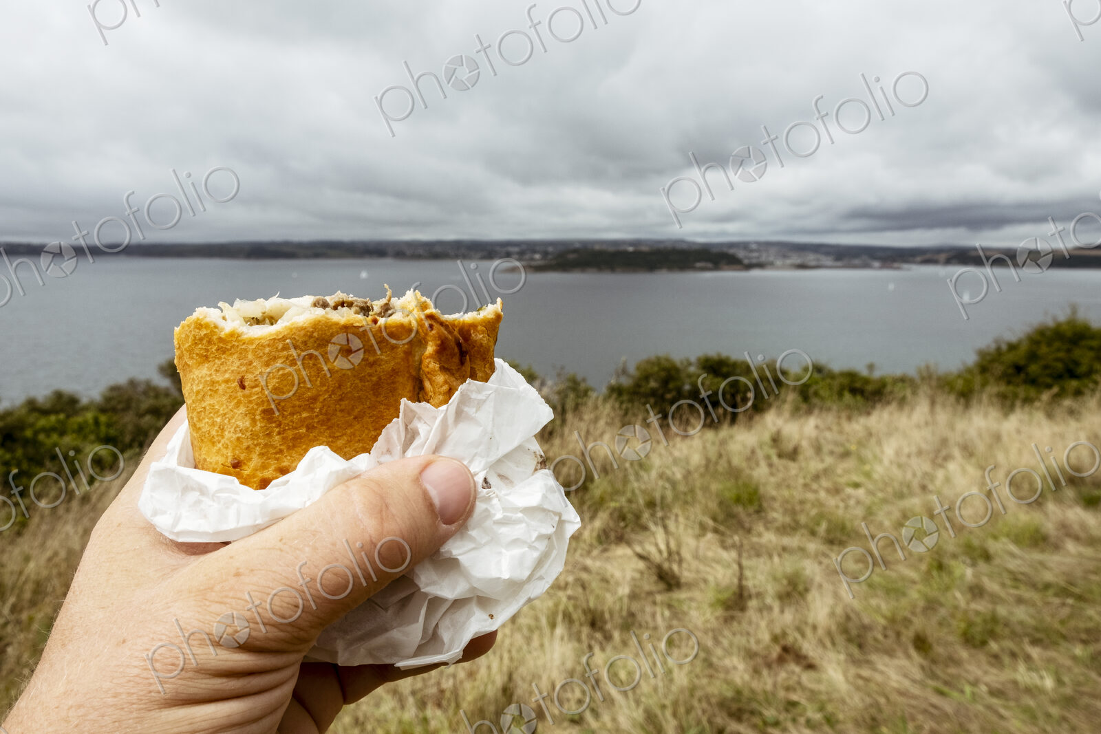 A hand holding a half eaten Cornish pasty.